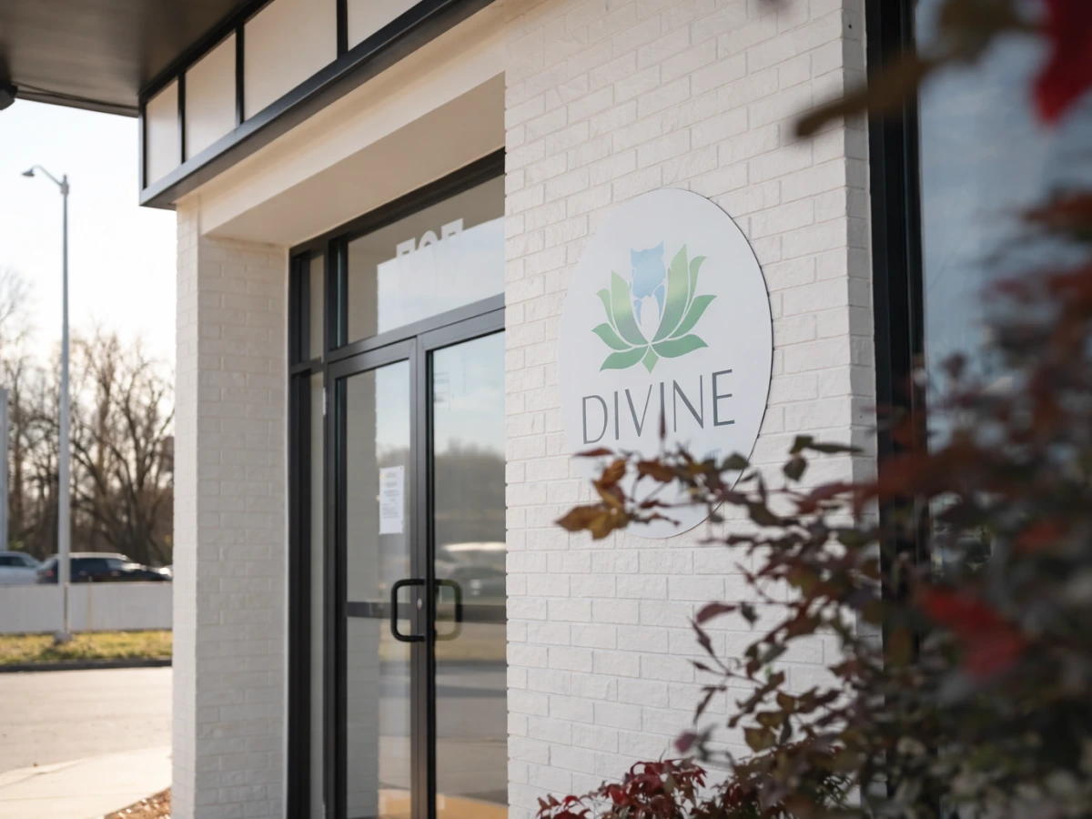 Divine dental practice exterior entrance with logo on white brick wall and glass doors